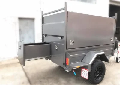A trailer with drawers and a canopy is parked in front of a building